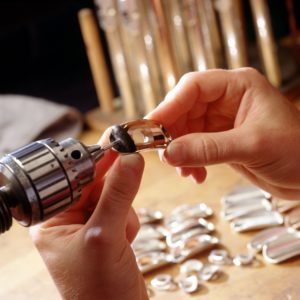 Two hands polishing a gold lip plate for a flute headjoint.